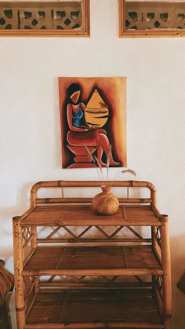 Tableau d'inspiration africaine au-dessus d'une console en rotin, sous des claustras